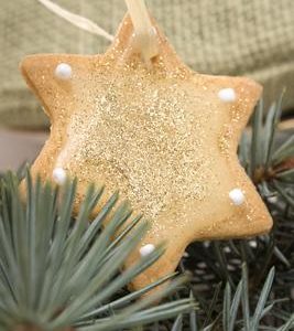 close up photo of star shaped sugar cookie hanging from Christmas tree branch