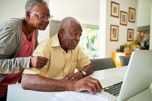 senior couple looking at laptop in their kitchen during medicare open enrollment