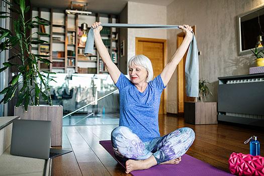 senior woman doing stretches on a yoga mat in her living room