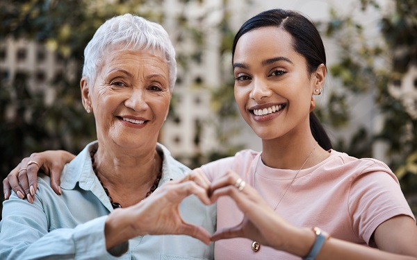 older mother and older daughter putting their hands together to make a heart shape